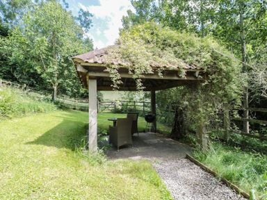 A gazebo with seating and a grill in the garden at The Stable in Deepdean near Ross-on-Wye