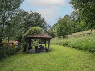 A gazebo with a barbecue and seating in a garden at The Stable Deepdean near Ross-on-Wye