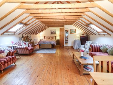 A loft bedroom with wooden beams striped sofas and a bed at Mrs Delaney's Loft in Ardfinnan near Clonmel County Tipperary