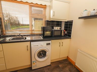 A kitchen with a washing machine and microwave at Moybella Lodge in Lisselton near Ballybunion, County Kerry