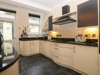A kitchen with curved cabinets black countertops and appliances at Morolwg in Llanaber near Barmouth
