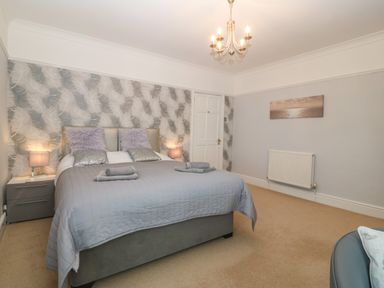 A bedroom with a double bed two bedside tables and lamps a door and a radiator at Morolwg in Llanaber near Barmouth