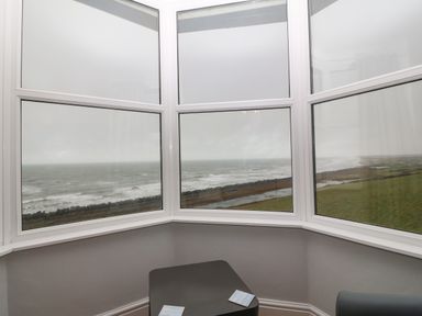 A bay window overlooking the sea and grassy coastline at Morolwg in Llanaber near Barmouth