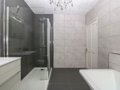 A bathroom with a walk in shower a sink and a bathtub with tiled walls and floor at Morolwg in Llanaber near Barmouth