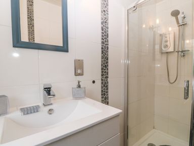 A bathroom with a sink a mirror and a glass-enclosed shower at Morolwg in Llanaber near Barmouth