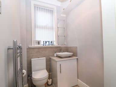 A bathroom with a toilet sink cabinet and a window with decorative items at Morolwg Llanaber near Barmouth