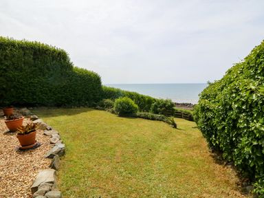 A garden with grass shrubs and potted plants overlooking the sea at Morolwg in Llanaber near Barmouth