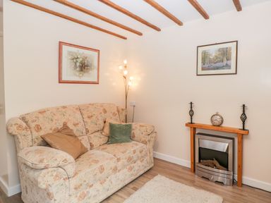 A sitting room with floral sofa and two framed pictures above a fireplace at Woods Edge in Mitcheldean