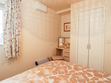 A bedroom with floral curtains bed with floral bedspread a vanity table with a mirror and stool and a closed white wardrobe at Woods Edge in Mitcheldean