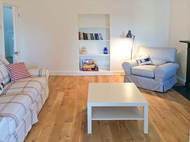 A living room with a couch, armchair, white coffee table, built-in bookshelf, and floor lamp at The Grange in Little Haven near Haverfordwest