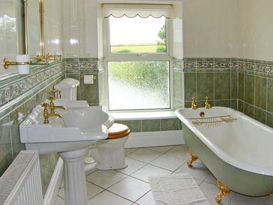 A bathroom with a pedestal sink toilet and clawfoot bathtub at The Grange in Little Haven near Haverfordwest