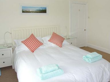 A bedroom with a double bed striped pillows folded towels bedside tables and a framed picture on the wall at The Grange in Little Haven near Haverfordwest