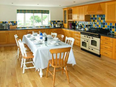 A kitchen with a dining table set for a meal and wooden cabinets at The Grange in Little Haven near Haverfordwest 