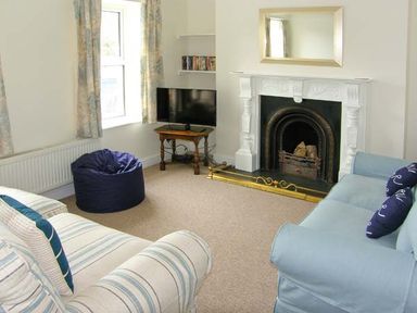 A living room with sofas a bean bag a fireplace and a television at The Grange in Little Haven near Haverfordwest 