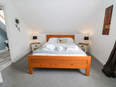 A bedroom with a bed and nightstands at Cariad Cottage in Cross Inn
