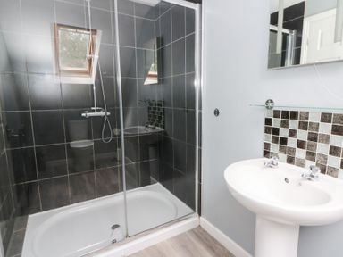 A bathroom with a shower, toilet, and sink at Cariad Cottage in Cross Inn