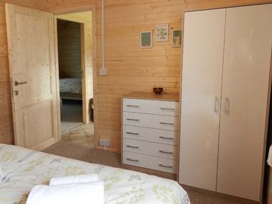 A bedroom with a bed linens folded on the bed a chest of drawers and a wardrobe at Pennylands Willow Lodge in Broadway