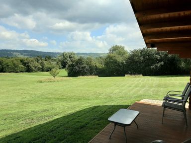 A backyard with a lawn chairs and a small table on a wooden deck at Pennylands Willow Lodge in Broadway