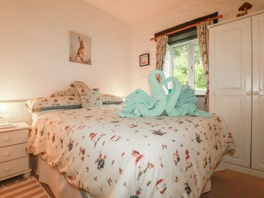 A bedroom with a double bed and decorative towels at Wagtail Cottage East Taphouse