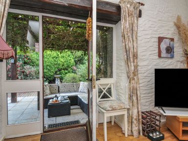 A living room with door and view of garden at Wagtail Cottage in East Taphouse