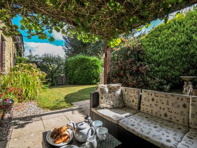 A garden with a sofa and tea set at Wagtail Cottage East Taphouse