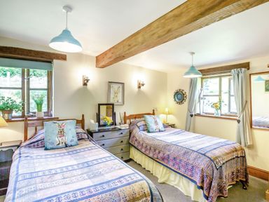 A bedroom with two single beds a chest of drawers and windows at Bwythyn Y Wennol Nantmor near Beddgelert