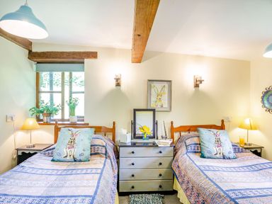 A bedroom with two single beds bedside tables and a chest of drawers at Bwythyn Y Wennol in Nantmor near Beddgelert