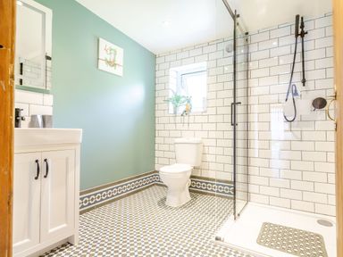 A bathroom with a toilet sink green wall tiled walls and floor and a glass shower at Bwythyn Y Wennol in Nantmor near Beddgelert