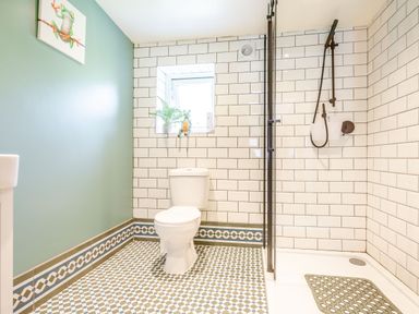 A bathroom with a toilet a walk in shower and tiled walls and floor at Bwythyn Y Wennol in Nantmor near Beddgelert