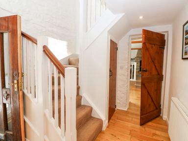 A hallway with carpeted stairs wooden doors and wooden floor at Farrier's Cottage in Garsdale