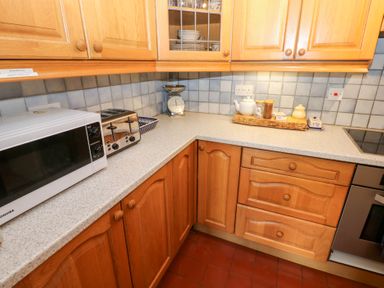 A kitchen countertop with a microwave toaster scale and jars on a tile backsplash at Farriers Cottage in Garsdale
