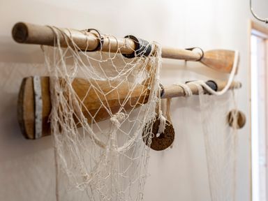 A pair of wooden oars with fishing nets hanging on a wall at Nectan in Mevagissey