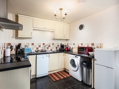 A kitchen with cabinets dishwasher washing machine refrigerator and microwave at Nectan in Mevagissey