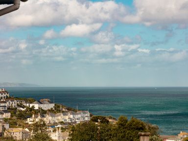 A coastal village with houses overlooking the sea under a partly cloudy sky at Nectan in Mevagissey