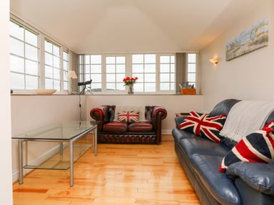 A living room with two leather sofas and a glass coffee table at The Well House Apartment in Watchet