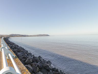 A sea view with a rocky shoreline and a metal railing on the left at The Well House Apartment in Watchet