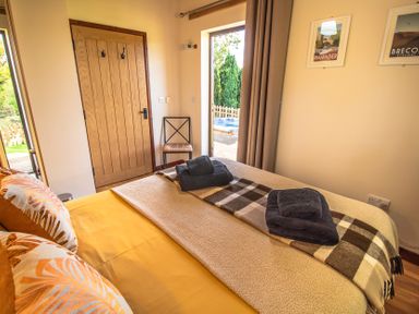 A bedroom with a bed and towels arranged at Sycamore Lodge Nantmel near Rhayader