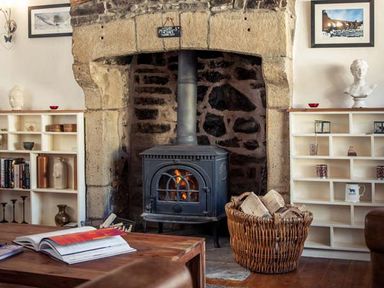A living room with a fireplace wood stove and bookshelves at Bastle House in Haltwhistle near Hadrians Wall
