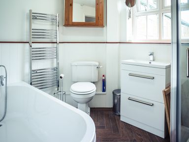 A bathroom with a bathtub toilet sink cabinet window and towel radiator at Bastle House in Haltwhistle near Hadrians Wall