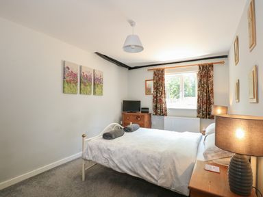 A bedroom with a double bed two bedside tables and a small TV on a wooden chest of drawers Hadleigh Farm Cottage Gayton