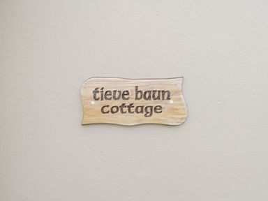A wooden sign with text tieve baun cottage mounted on a plain wall at Tieve Baun in Ballintrillick near Kinlough County Sligo