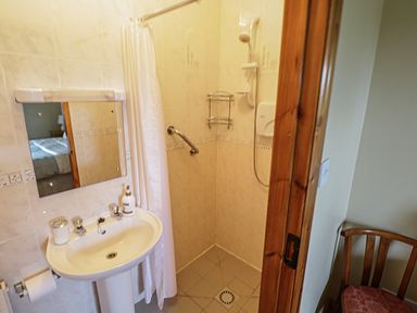 A small bathroom with a pedestal sink mirror and walk in shower at Tieve Baun in Ballintrillick near Kinlough County Sligo
