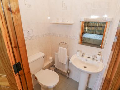 A small bathroom with a toilet sink mirror towel and shelf with glasses at Tieve Baun in Ballintrillick near Kinlough County Sligo