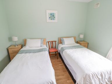 A bedroom with two single beds a wooden chair between them and two bedside tables with lamps at Tieve Baun in Ballintrillick near Kinlough County Sligo