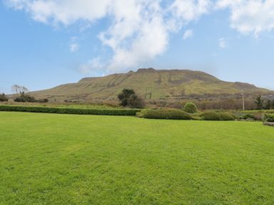 A grassy lawn with shrubs and a mountain in the background at Tieve Baun in Ballintrillick near Kinlough County Sligo
