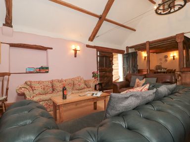 A living room with sofas a wooden coffee table and bookshelf with board games at The Barn in Bicknoller