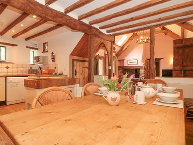 A kitchen and dining area with wooden beams and a flower vase on the table at The Barn in Bicknoller