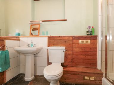 A bathroom with a toilet sink a small mirror and a glass shower at The Barn in Bicknoller