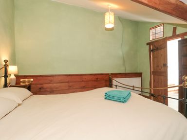 A bedroom with a bed lamp folded towels wooden door and exposed wooden beam at The Barn in Bicknoller