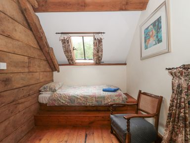 A bedroom with a single bed under a window and a wooden chair at The Barn in Bicknoller